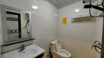 Ein Badezimmer mit Waschbecken, Spiegel, Toilette und Duschbereich.