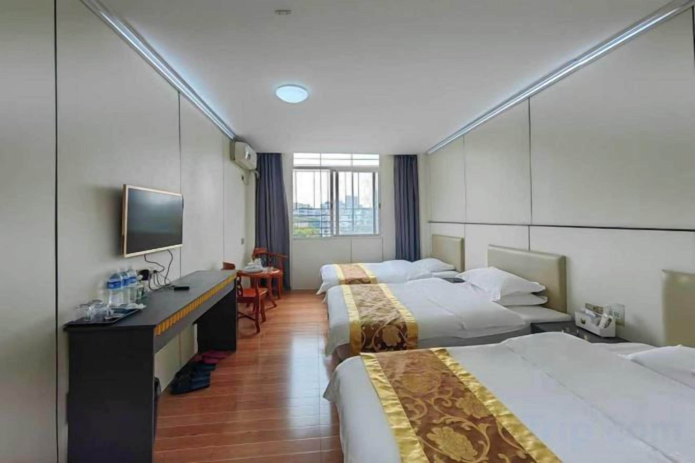 A hotel room with two beds, a desk with a TV, and a window with a city view.