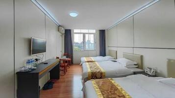 A hotel room with two beds, a desk with a TV, and a window with a city view.
