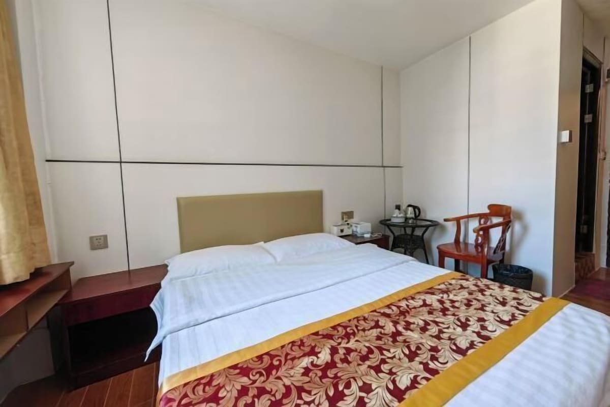 Habitación de hotel con cama, escritorio, silla y una mesita.