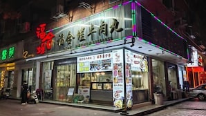 Un restaurante con un letrero de neón e iluminación en el toldo.