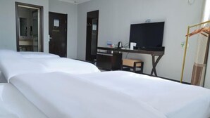 Habitación de hotel con dos camas, un escritorio con computadora, televisor y espejo.