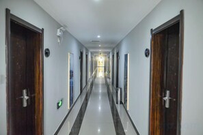Un largo pasillo estrecho en un hotel, con puertas a ambos lados que dan a habitaciones individuales.