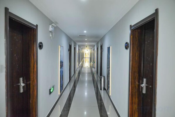 A long, narrow hotel corridor with doors on both sides, leading to individual rooms. - Yijiaqin Hotel (Huangshan City)