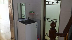 Una kitchenette compacta con un lavamanos, espejo y una pequeña estantería.