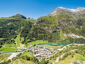 A mountainous landscape with a small village nestled among green hills and a river.