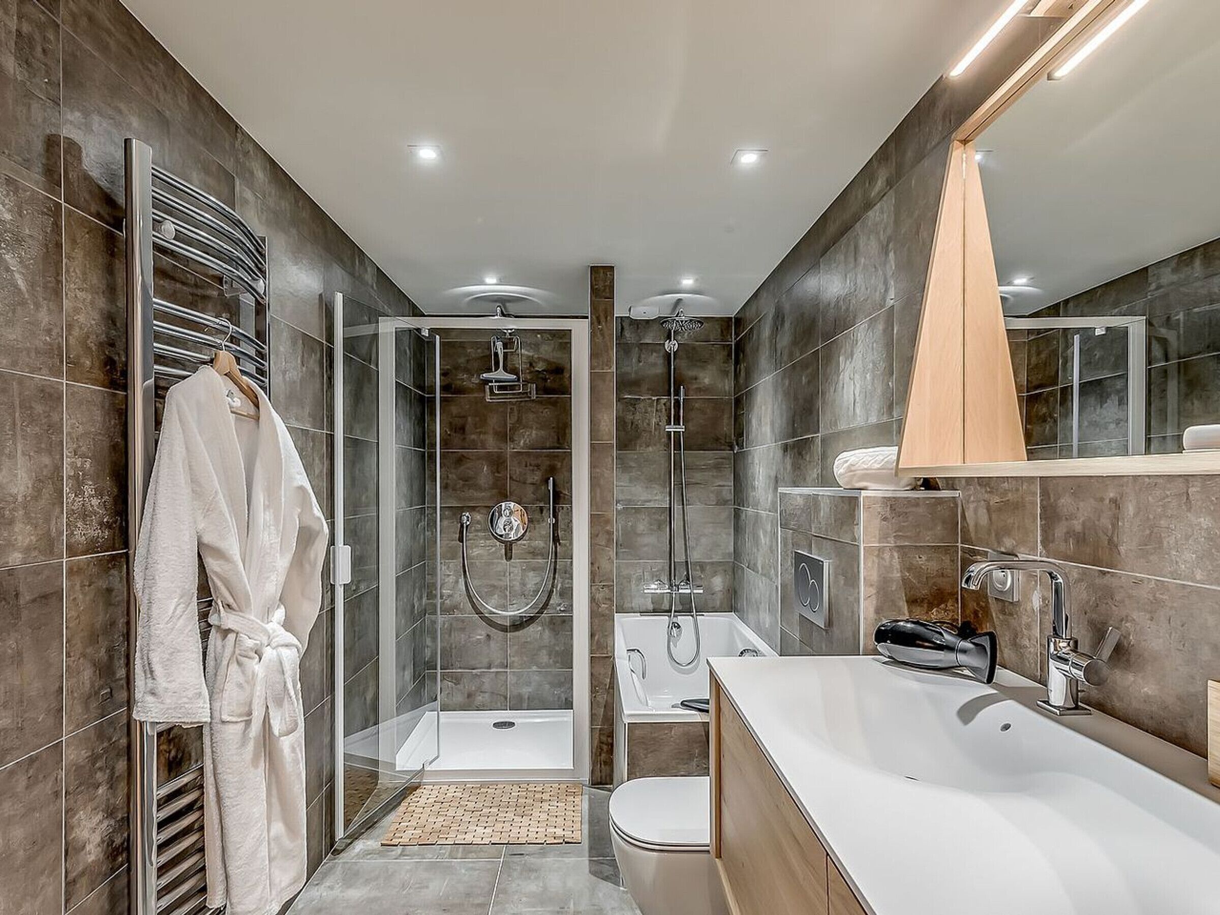 A modern bathroom with a glass-enclosed shower, a separate bathtub, and a vanity with a mirror.