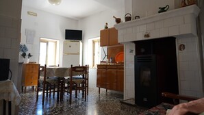 Une cuisine avec un coin repas, un téléviseur, une cheminée et un sol carrelé.