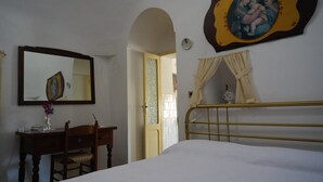 Une chambre à coucher avec un lit, un bureau et une chaise, un miroir et un tableau accroché au mur.