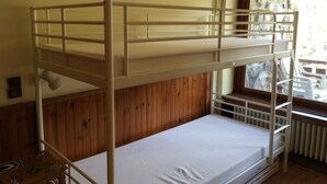 Une chambre avec un lit superposé, un mur en bois et une fenêtre.