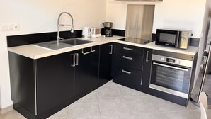 A modern kitchen with black cabinets, a stainless steel range hood, a microwave, and a coffee maker. - Bright house villa (Andernos-les-Bains)