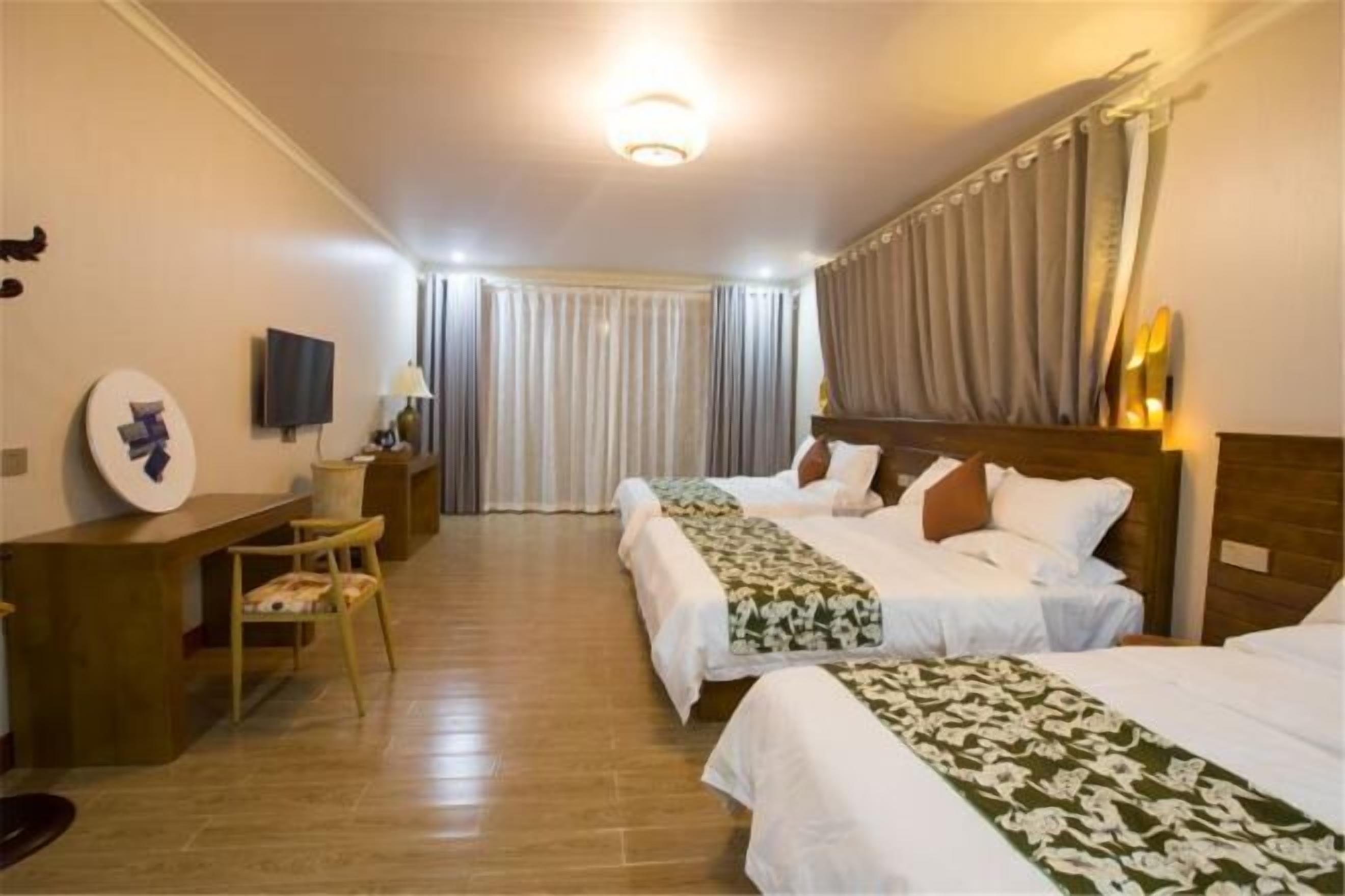Una habitación de hotel con dos camas, un escritorio, una silla, un televisor y una cortina.