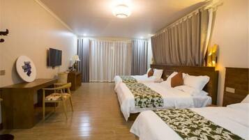 Una habitación de hotel con dos camas, un escritorio, una silla, un televisor y una cortina.