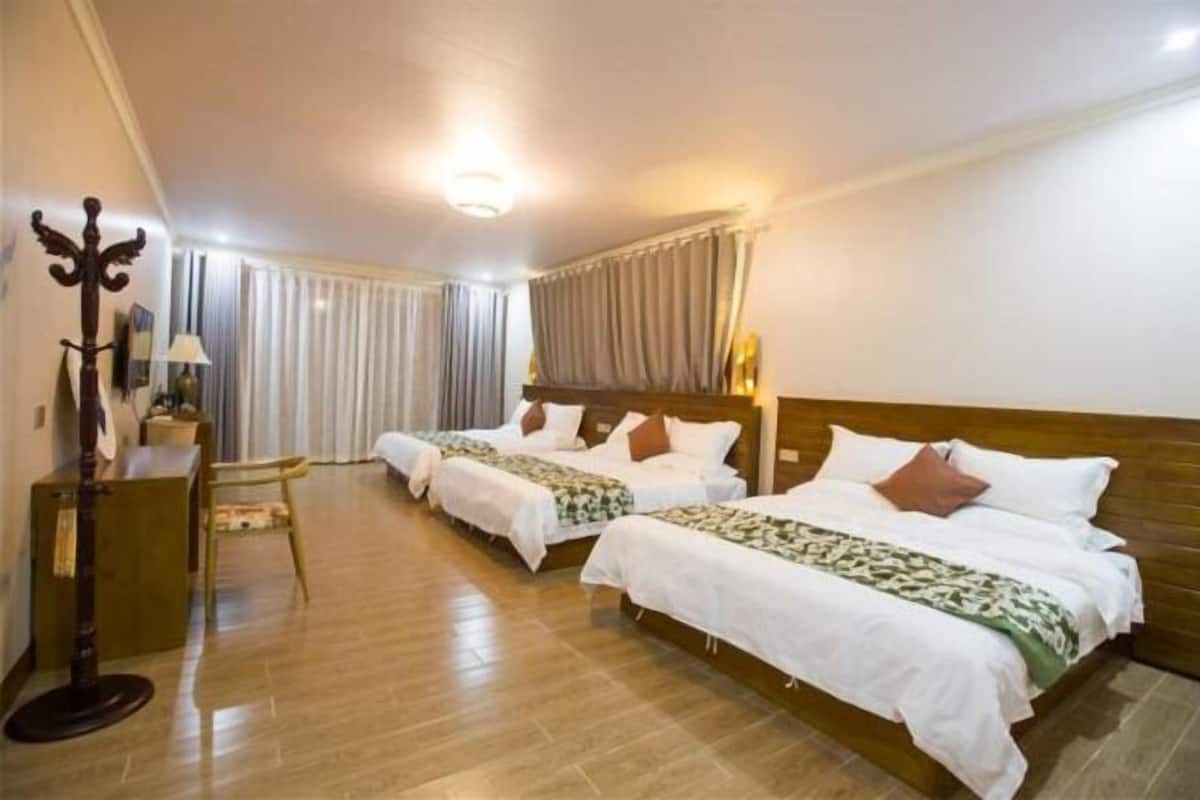 Ett hotellrum med två separata sängar, en sänggavel i trä, ett skrivbord med en lampa och en stol.
