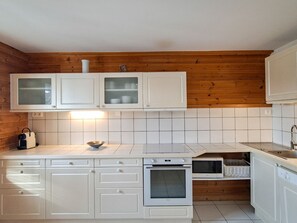 A kitchen with white cabinets, a microwave, an oven, and a sink.
