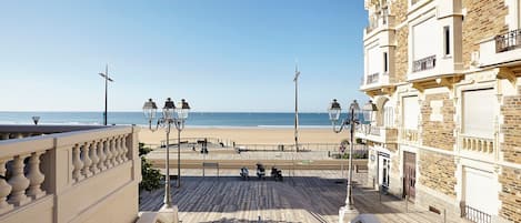 Un paseo marítimo con vistas a la playa, una senda peatonal y un edificio con balcones.