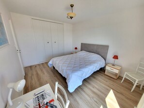 A bedroom with a bed, a nightstand, a chair, a desk with a lamp, and a wardrobe. - Renovated T3 apartment sea view with garage and WIFI (Les Sables-d'Olonne)