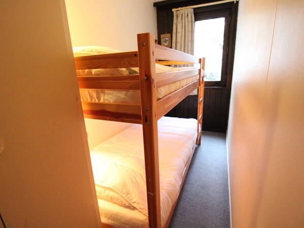 A bunk bed in a room with a window and curtains.