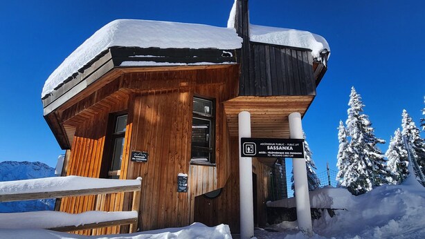 Une cabane en bois avec une pancarte indiquant qu’il s’agit d’une station d’ascenseur public appelée SASSANKA.