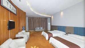 Habitación de hotel con dos camas, un sofá, un televisor y un ventanal con cortinas.