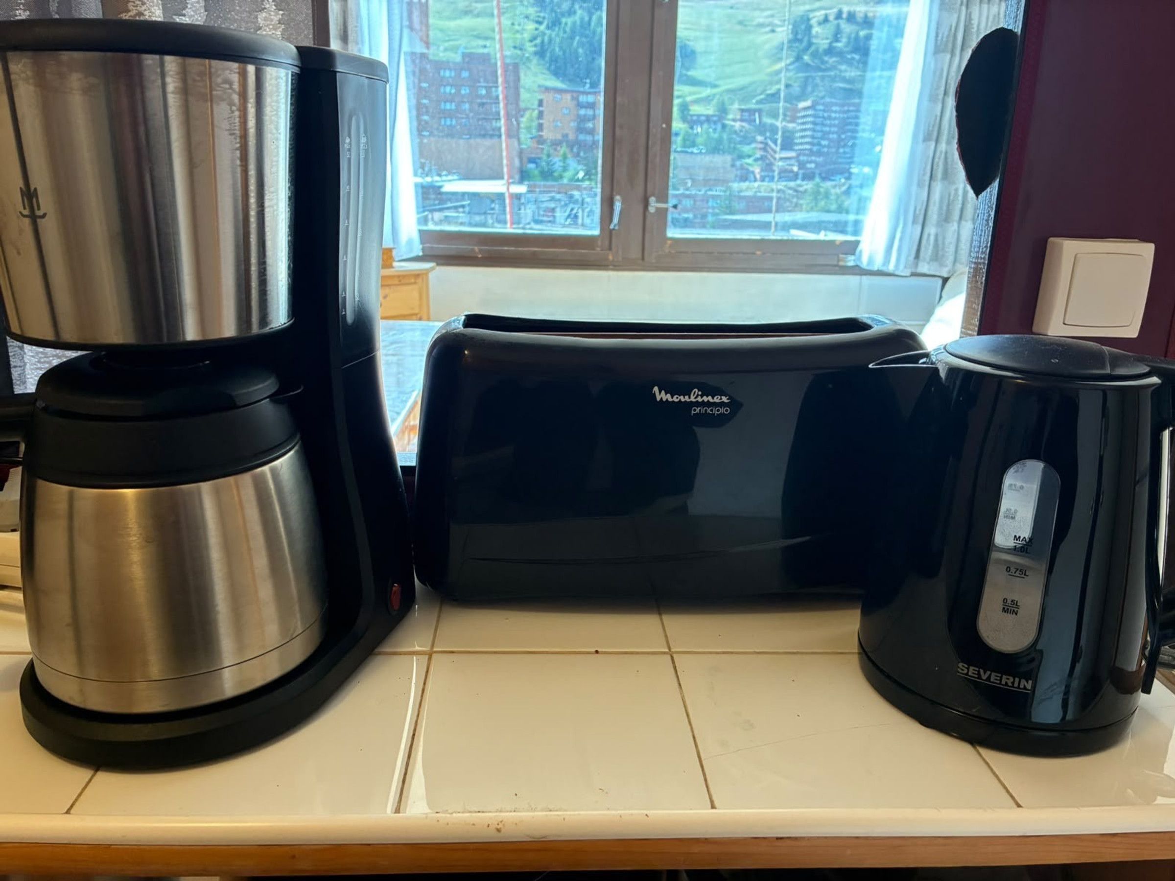 Un piano di lavoro in cucina con una macchina da caffè, un tostapane e un bollitore.