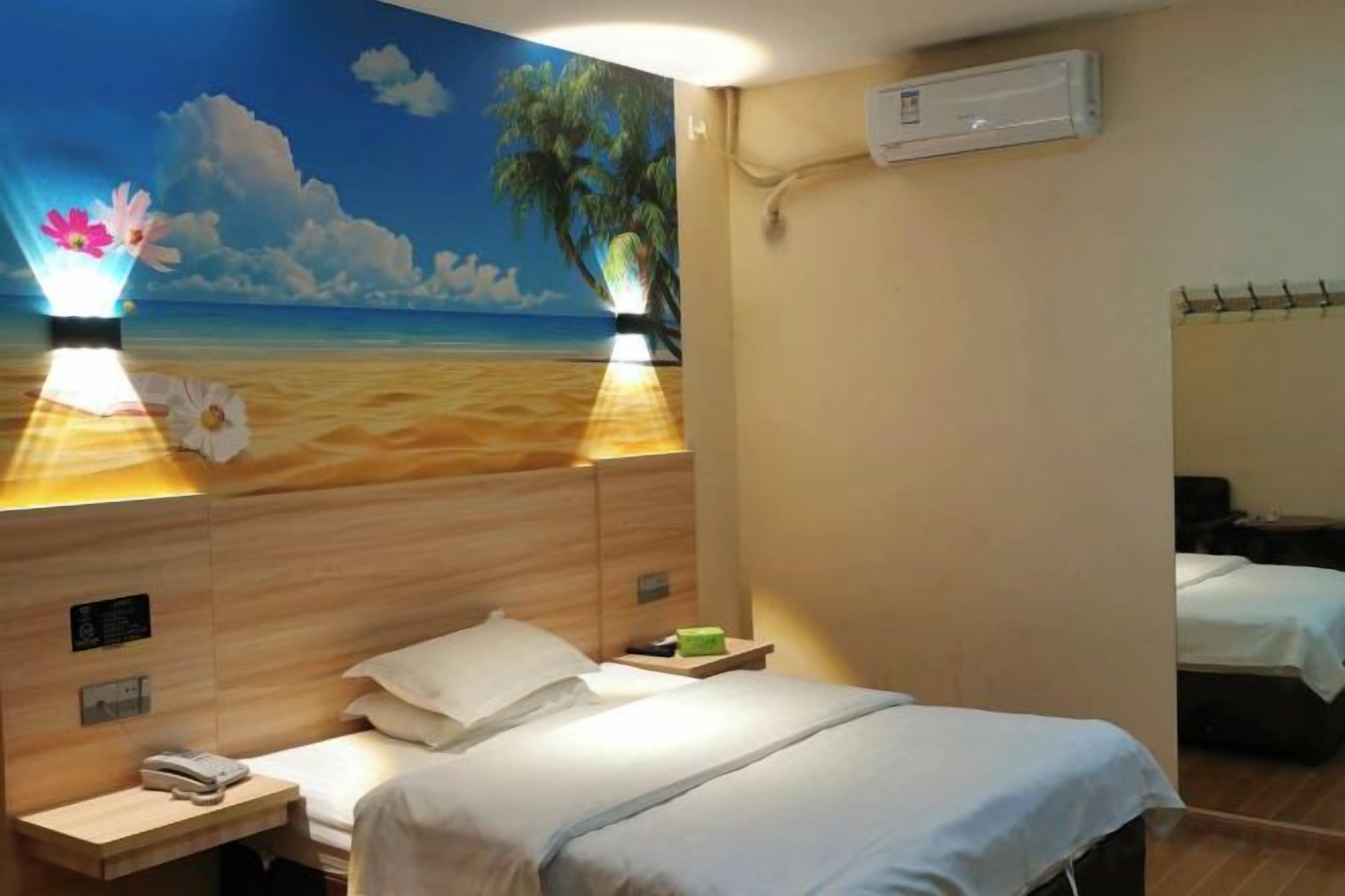 Habitación de hotel con un mural de playa, una cama con ropa blanca, una mesita de noche con teléfono y un aire acondicionado de pared.