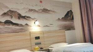 A hotel room with a large wall mural of mountains and birds, a wooden headboard, two beds, and a bedside table with a lamp. - Zhixing Business Hotel (Quanzhou)