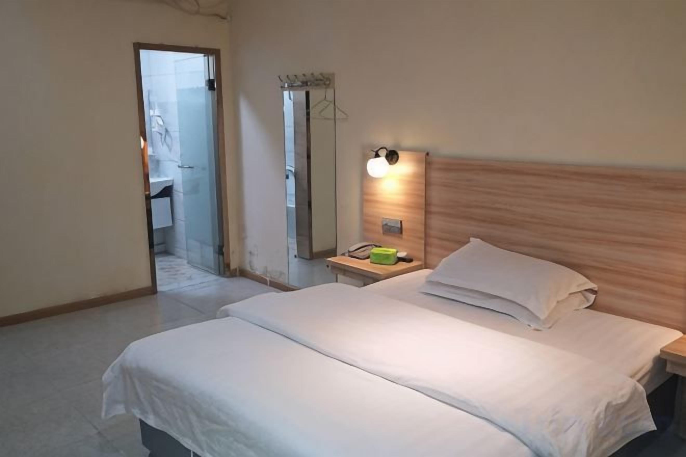 Een hotelkamer met een bed, nachtkastje en spiegel.