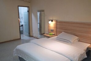 A hotel room with a bed, bedside table, and a mirror. - Zhixing Business Hotel (Quanzhou)