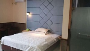 A hotel room with a bed, bedside table, lamp, and an air conditioning unit. - Zhixing Business Hotel (Quanzhou)