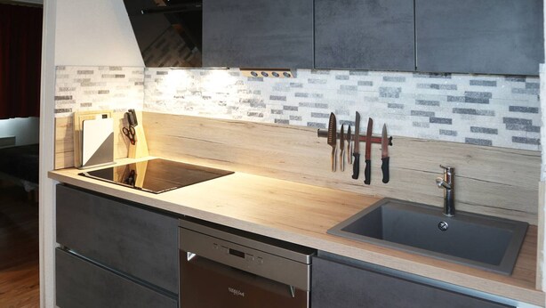 A modern kitchen with a wooden countertop, a built-in dishwasher, and a backsplash with a brick pattern. - Renovated apartment for 8 with pool, jacuzzi and sauna in Les Orres (Les Orres)