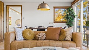 Ein gemütliches Wohnzimmer mit einem braunen Ledersofa, einem runden weißen Couchtisch und einer Pendelleuchte.