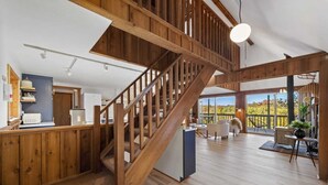 Ein großzügiger Wohnbereich mit einer Holztreppe, einer Küchenzeile und einem Balkon mit Aussicht.