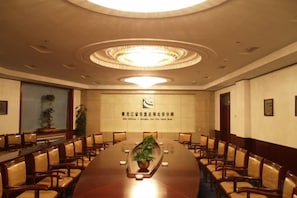 Un salón de conferencias con una larga mesa, sillas y un logotipo en la pared.