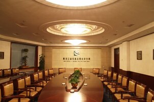 Un salón de conferencias con una larga mesa, sillas y un logotipo en la pared.