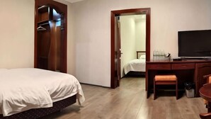 A hotel room with a bed, a desk, a television, and a door leading to another room. - Longken Bei'an Hotel (Bei'an)