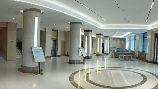 A spacious lobby with high ceilings, large columns, and a central circular design on the floor. - Longken Bei'an Hotel (Bei'an)