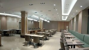 A modern hotel lobby with a long dining area, a reception desk, and a seating area with a green wall. - Longken Bei'an Hotel (Bei'an)
