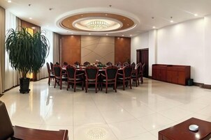 Un salón de conferencias con una mesa redonda, sillas, una planta en maceta y un armario.
