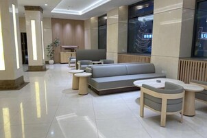 Un vestíbulo moderno con zona de estar, mostrador de recepción y un ventanal grande.