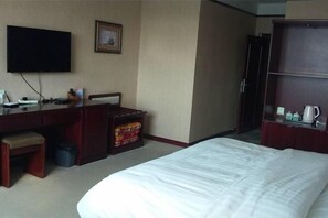 Una habitación de hotel con cama, escritorio, televisor y armario.