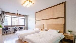 A hotel room with two beds, a wooden headboard, a small table, and a chair. - Qiqi Inn (Xinyang)