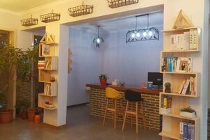 A cozy bar area with a brick counter, wooden chairs, and a bookshelf filled with books.
