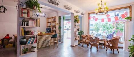 Un ambiente accogliente con zona bar, libreria, mobili in vimini e piante in vaso.