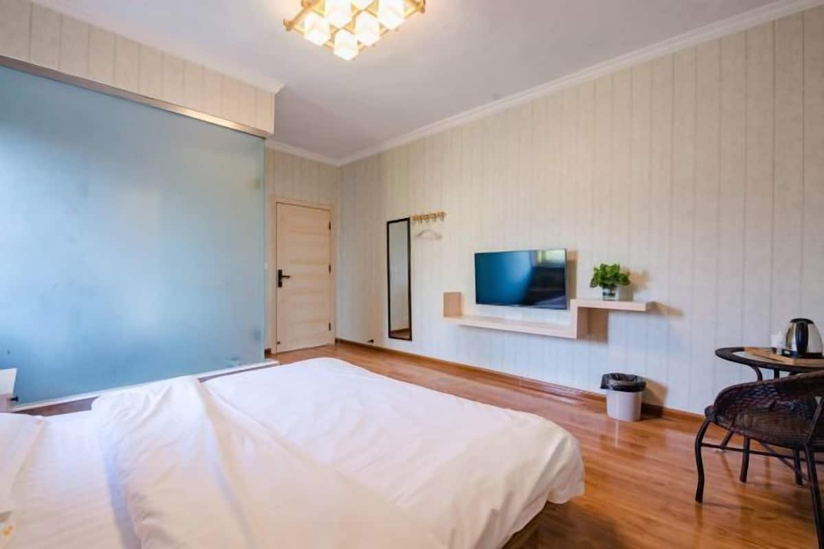 A hotel room with a bed, a television mounted on the wall, a small table with a plant, and a chair.