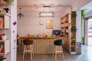 Una zona de bar con taburetes, una pared de ladrillo y una estantería de madera.