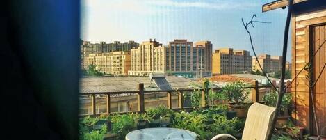A balcony with a view of buildings, a table, and chairs.