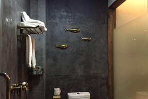 Ein Badezimmer mit dunkler Wand, einem Handtuchhalter mit Handtuch und einer Toilette.