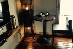 A small round table with a chair, a television on a shelf, a wicker chair, and a window with a view. - Chengzhong Xiaozhu Holiday House (Zhangjiajie Tianmenshan Bus Station Railway Station) (Zhangjiajie)