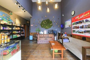 A café interior with a wooden floor, a sofa, a table, and a wall-mounted clock. - Chengzhong Xiaozhu Holiday House (Zhangjiajie Tianmenshan Bus Station Railway Station) (Zhangjiajie)